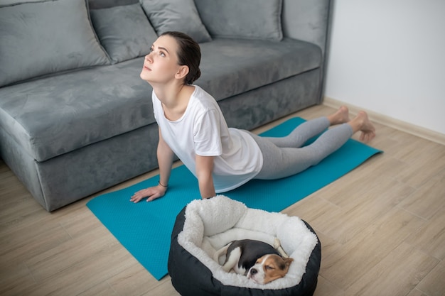 Ralentizando. Una mujer joven que tiene un entrenamiento mientras su cachorro duerme cerca