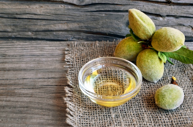 Rama de almendras nueces y aceite de almendras en un recipiente de vidrio sobre fondo de madera vieja.