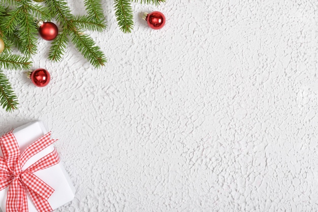 Una rama de un árbol de Navidad con bolas de Navidad y un regalo. Fondo para Navidad y año nuevo. Una tarjeta navideña con un lugar para el texto. Diseño plano, vista superior, lugar para copiar.