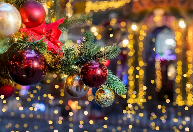 Rama de árbol de Navidad decorada con adornos de adornos navideños bolas y guirnaldas de luces borrosas en el fondo