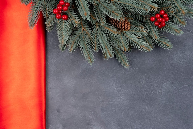 Rama de árbol de Navidad con frutos rojos y adornos sobre fondo de pared de hormigón gris