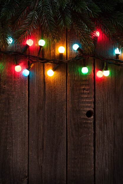 Rama de árbol de Navidad y luces de colores sobre fondo de madera. Ver con espacio de copia