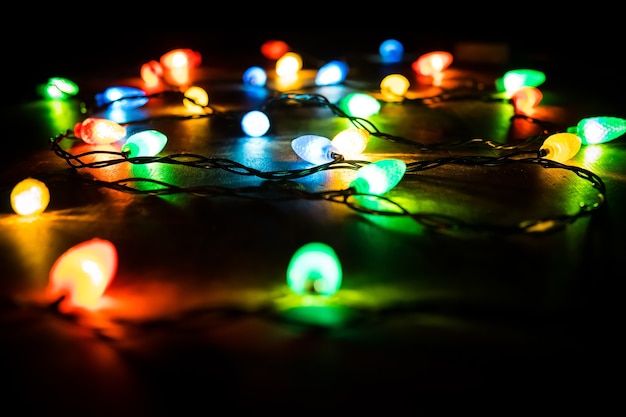 Rama de un árbol de Navidad y luces sobre fondo de madera. Ver con espacio de copia. Luces de colores en una guirnalda de Navidad en la oscuridad de la noche