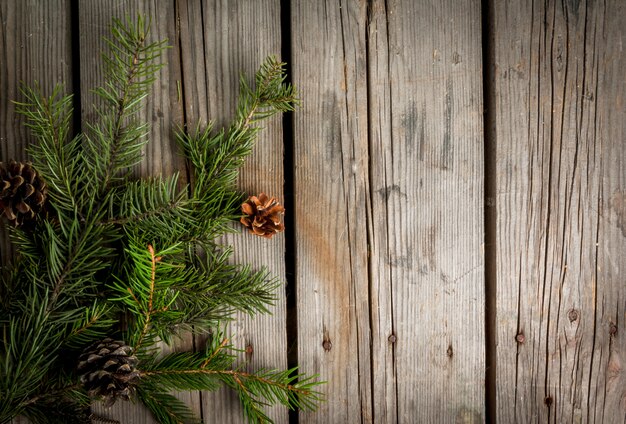 Rama de árbol de Navidad y piñas en la mesa de madera vieja