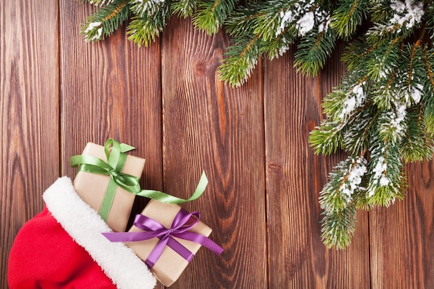 Rama de árbol de navidad y sombrero de santa con cajas de regalo.