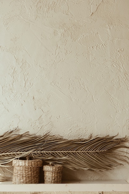 Foto rama de hoja de palma seca y ataúdes de ratán en muro de hormigón