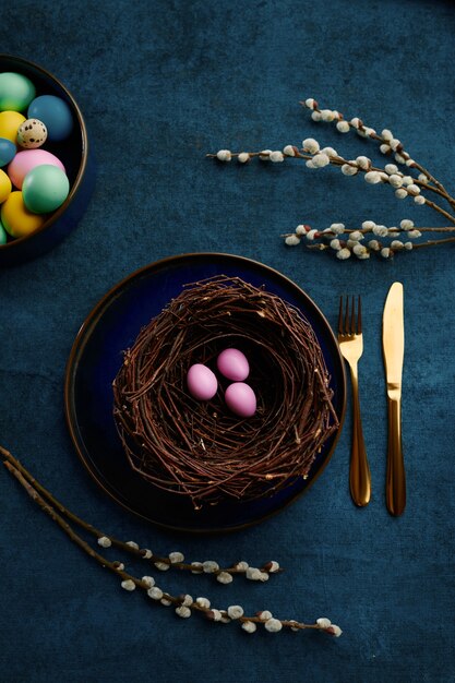 Rama de sauce floreciente, huevos de pascua en nido y vajilla. Flor de árbol de primavera y comida pascual, decoración floral fresca para celebración navideña, símbolo de evento