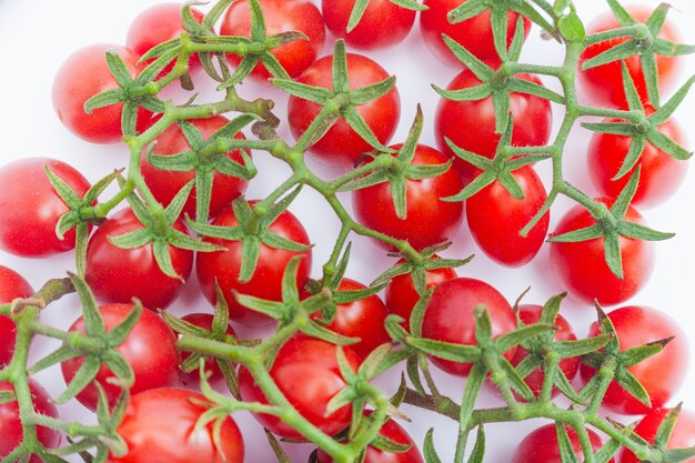 Rama de tomates de cereza frescos aislados en la vista de la parte superior blanca