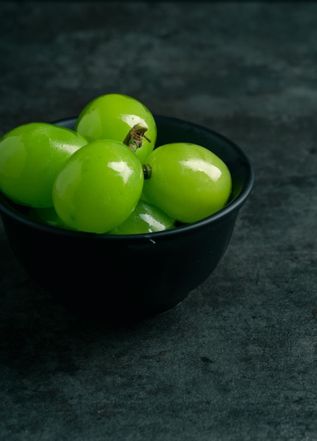 Una rama de uvas jugosas verdes en un plato con espacio de copia Fondo negro Vista frontal Lugar para escribir Adecuado para el verano