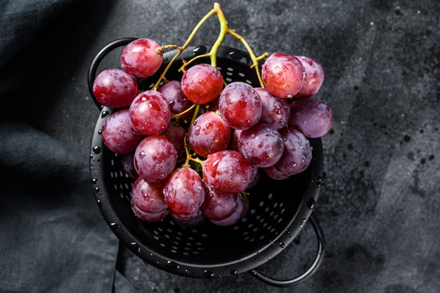 Una rama de uvas rojas jugosas en un colador. .