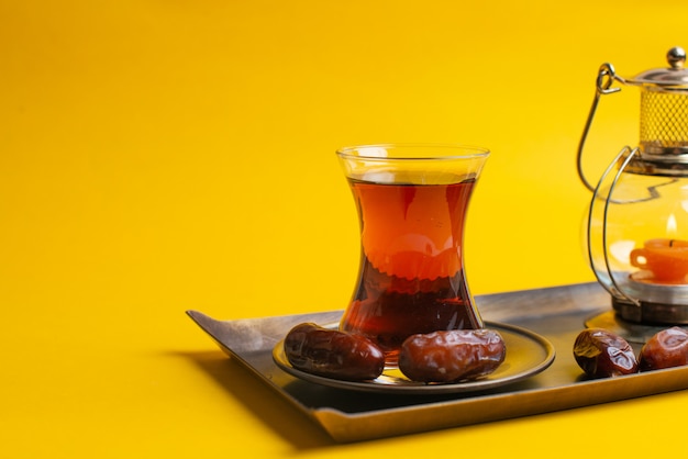 Ramadán Kareem festivo, cerca de las fechas en un plato con una lámpara de vela oriental y una taza de té negro