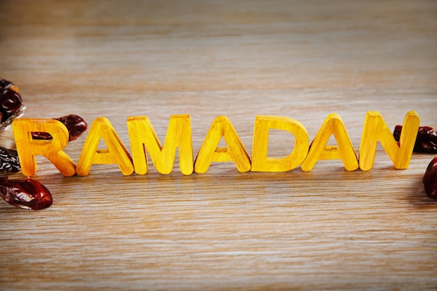 Ramadan-Wort mit Holzbuchstaben und trockenen Datteln auf dem Tisch