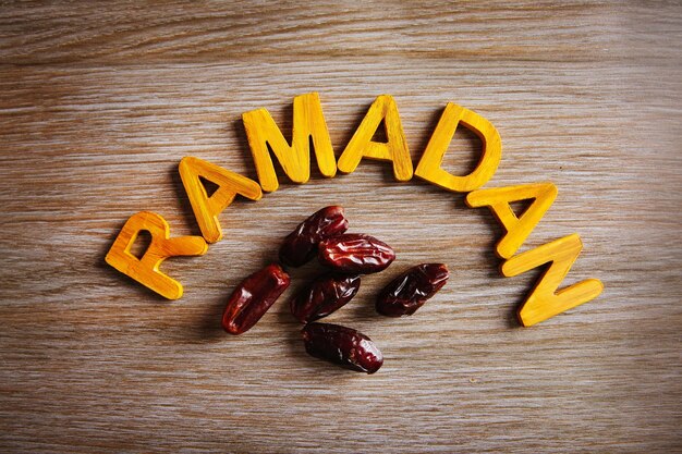 Ramadan-Wort mit Holzbuchstaben und trockenen Datteln auf dem Tisch
