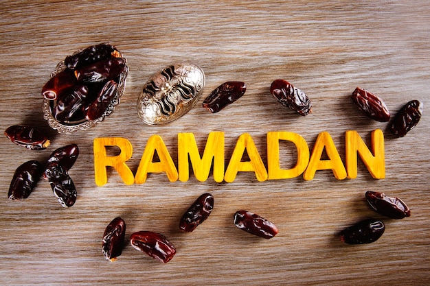 Ramadan-Wort mit Holzbuchstaben und trockenen Datteln auf dem Tisch