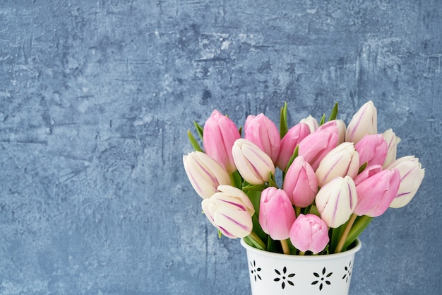 Ramalhete cor-de-rosa das tulipas no vaso branco no azul.