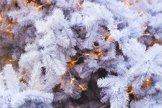 Ramas de abeto blanco de un árbol de Navidad artificial con luces amarillas. Fondo y copia espacio.