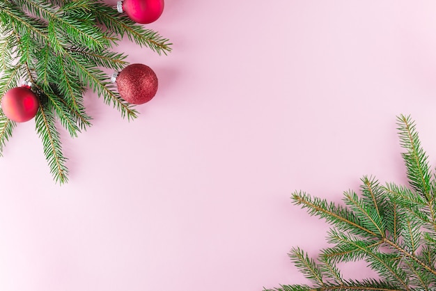Ramas de abeto con bolas de Navidad rojas sobre un fondo rosa Navidad y año nuevo