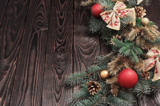 Ramas de abeto con decoración navideña sobre fondo antiguo de madera oscura.