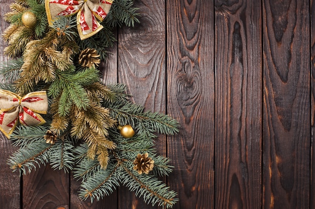 Ramas de abeto con decoración navideña sobre fondo antiguo de madera oscura.