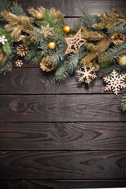 Ramas de abeto con decoración navideña sobre fondo antiguo de madera oscura.