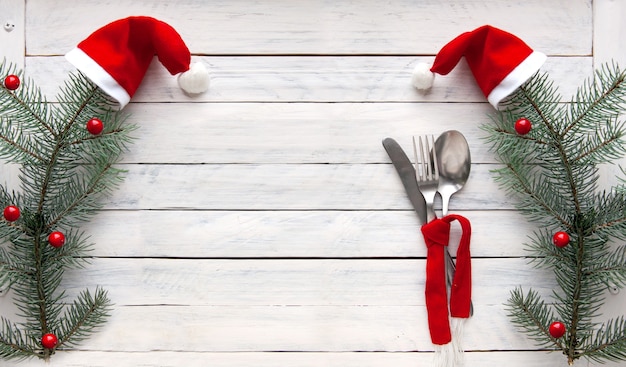 Ramas de abeto con gorro rojo y cubiertos en una bufanda Concepto navideño Decoración para el menú de Año Nuevo