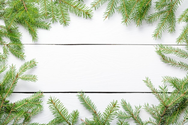 Ramas de abeto de Navidad en tablero de madera rústico blanco con espacio de copia