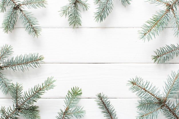 Ramas de abeto sobre un fondo blanco de madera Minimalismo navideño Espacio de copia Vista superior plana