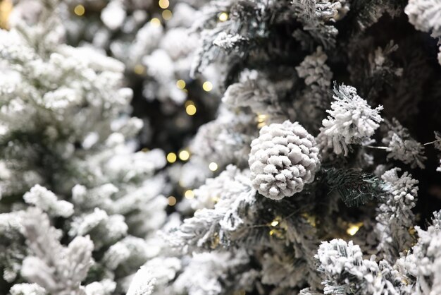Ramas de árbol de navidad helado con conos y luces de guirnaldas como fondo de navidad