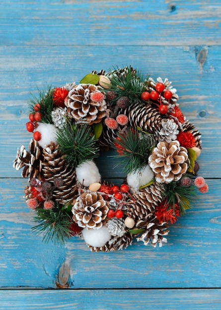 Ramas de los árboles de Navidad con conos en una tabla de madera oscura contra un muro de hormigón gris.