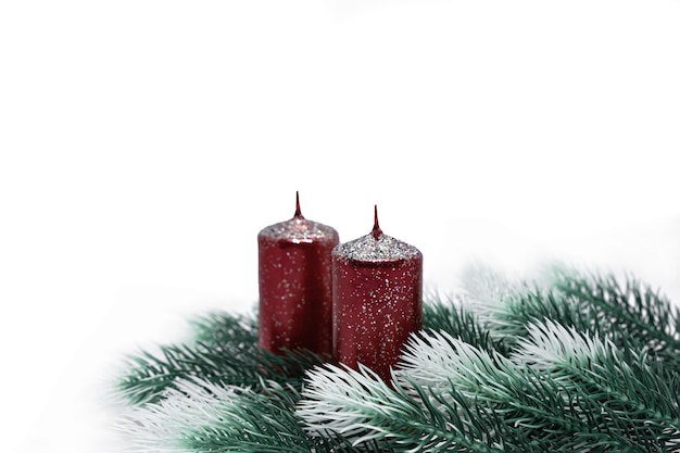 Ramas de los árboles de Navidad con efecto nieve y velas rojas