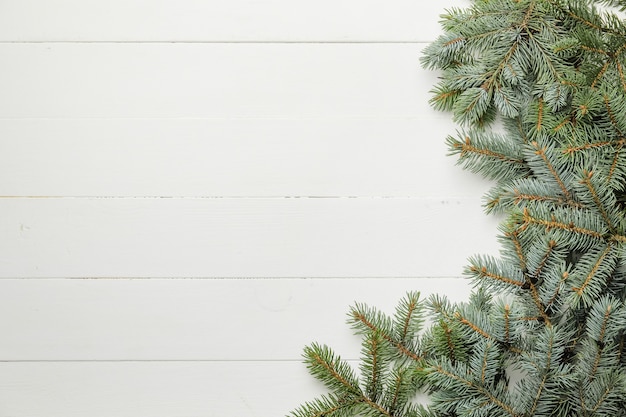 Ramas de los árboles de Navidad en la superficie de madera blanca