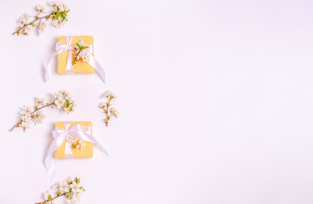Ramas de cerezo en flor con cajas para regalos sobre un fondo blanco y copie el espacio. Sentar planas, 8 de marzo, día de la madre, banner. Vista desde arriba