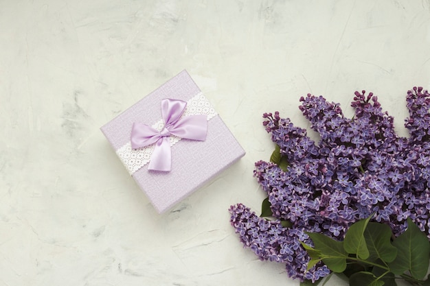 Ramas de color lila, caja de regalo sobre una superficie de piedra clara. Concepto de primavera. Vista plana, vista superior