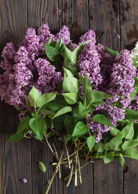 Ramas de flores lilas en la mesa de madera oscura.