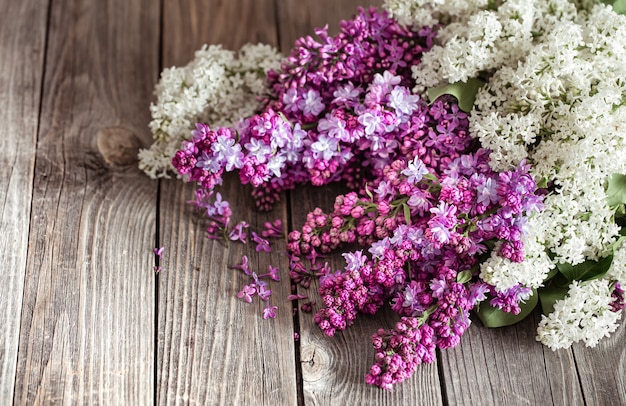 Ramas de lilas frescas en flor sobre una mesa de madera oscura.