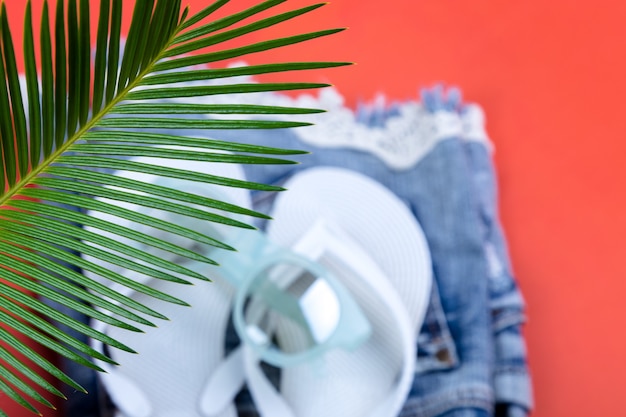 Ramas de palmeras tropicales con un conjunto borroso de accesorios de cosas de mujer para la temporada de playa