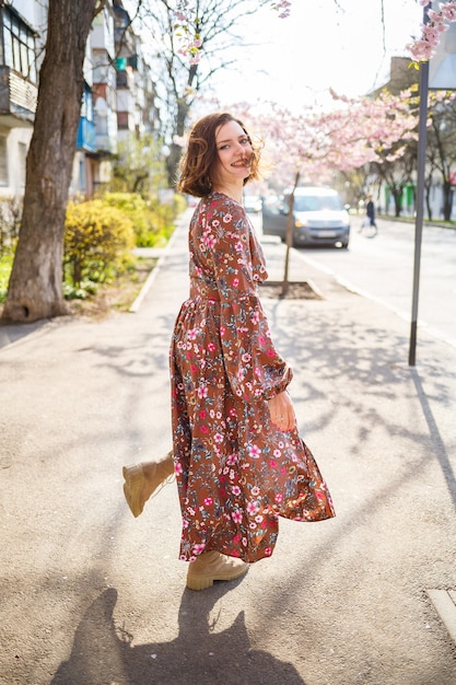 Ramas de Sakura con flores en un árbol en las calles de la ciudad. Chica mujer feliz girando en la calle con flor de sakura. Sakura florece.