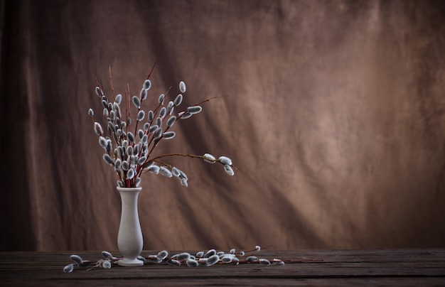 Foto ramas de sauce de primavera en florero sobre fondo marrón oscuro