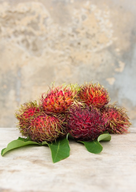 Rambután fresco sobre fondo de madera, fruta asiática de Tailandia