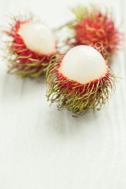 Foto rambután en la mesa de madera blanca, rambután rojo pelado