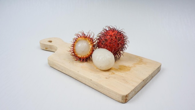 Foto rambután pelado en una cesta sobre tabla de cortar de madera