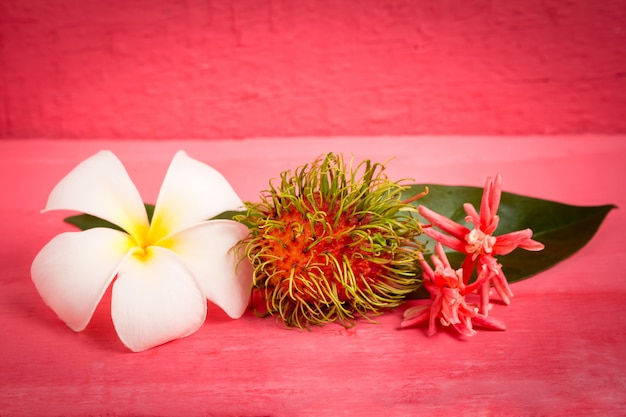 Rambutanfrucht auf hölzernem Farbrosa mit Blume