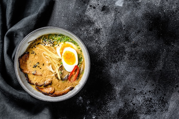 Ramen asiatische Nudelsuppe mit Rinderzungenfleisch, Pilzen und eingelegtem Ajitama-Ei. Schwarzer Hintergrund. Draufsicht. Speicherplatz kopieren