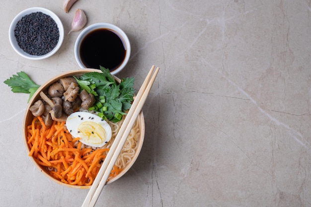 Ramen de sopa de macarrão em uma tigela branca com cenouras de ovo de galinha cogumelos em um fundo de pedra clara