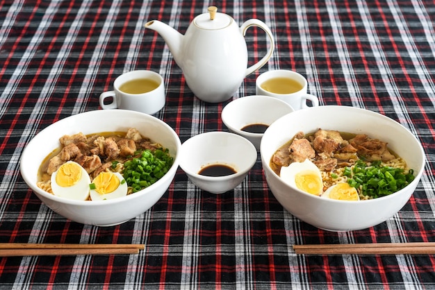 Ramen japonês com frango e molho de soja na mesa com bule e chá verde