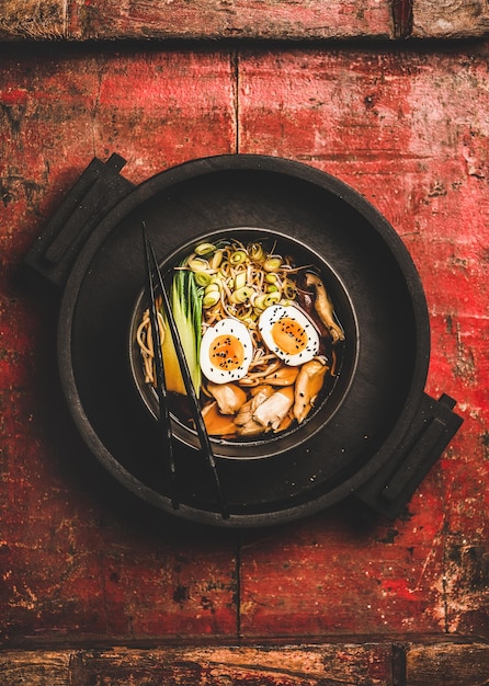 Ramen-Suppe mit Hühnchen und Shiitake-Pilzen in schwarzer Schüssel