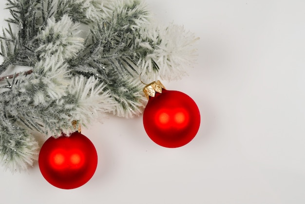 Una ramita de abeto decorado con bolas de Navidad rojas aisladas en blanco.