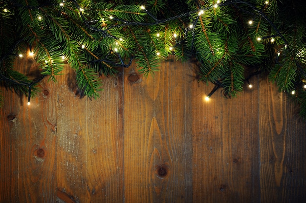 Foto ramitas de abeto con luces de navidad sobre fondo de madera