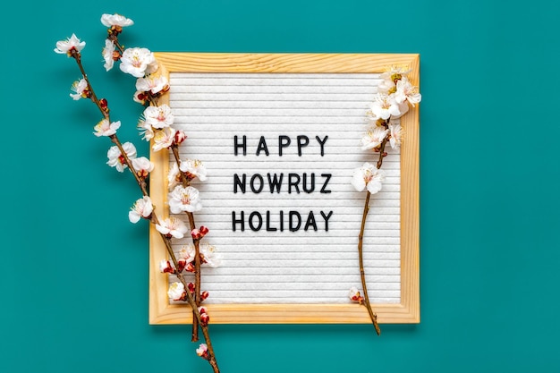 Ramitas del árbol de albaricoque con flores y Texto Feliz Nowruz Vacaciones Concepto de primavera llegó