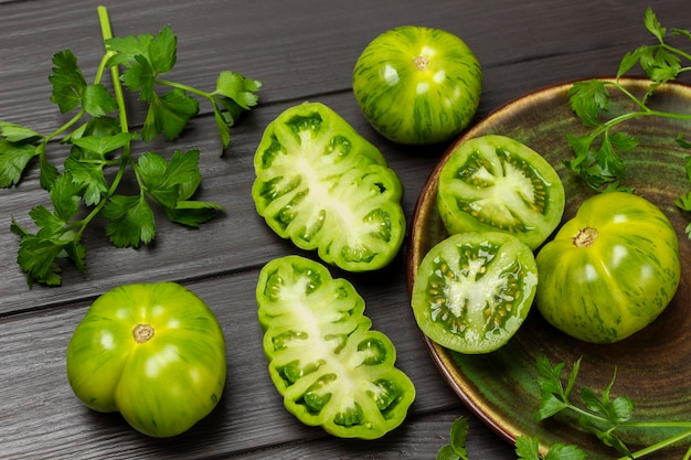 Ramitas de perejil tomates verdes en un plato y sobre la mesa